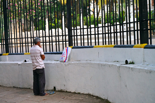 A Sinhalese man stopping to pray to Buddha while passing by the Temple of the Tooth in Kandy.